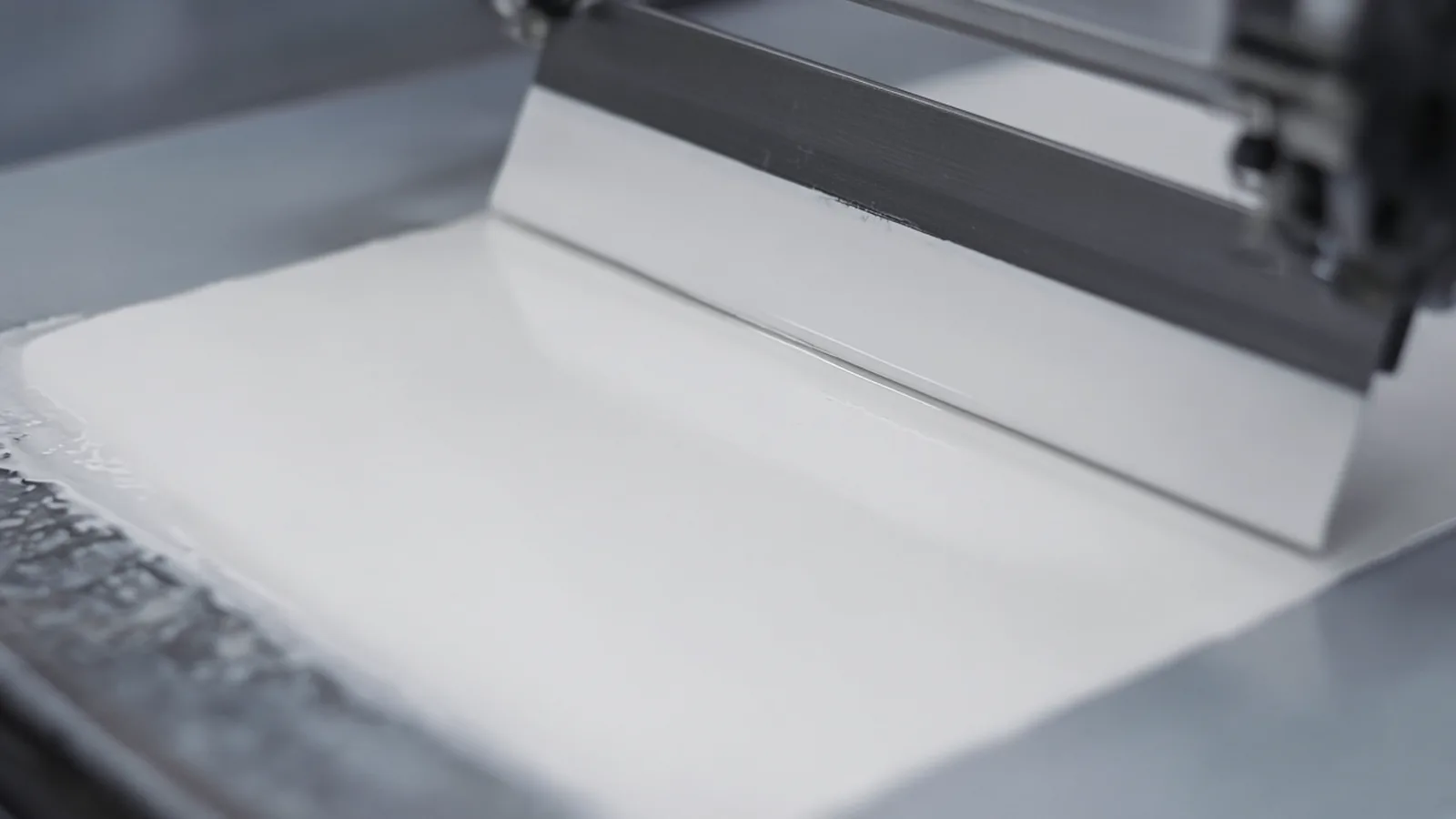 A blade laying down a smooth white coating
